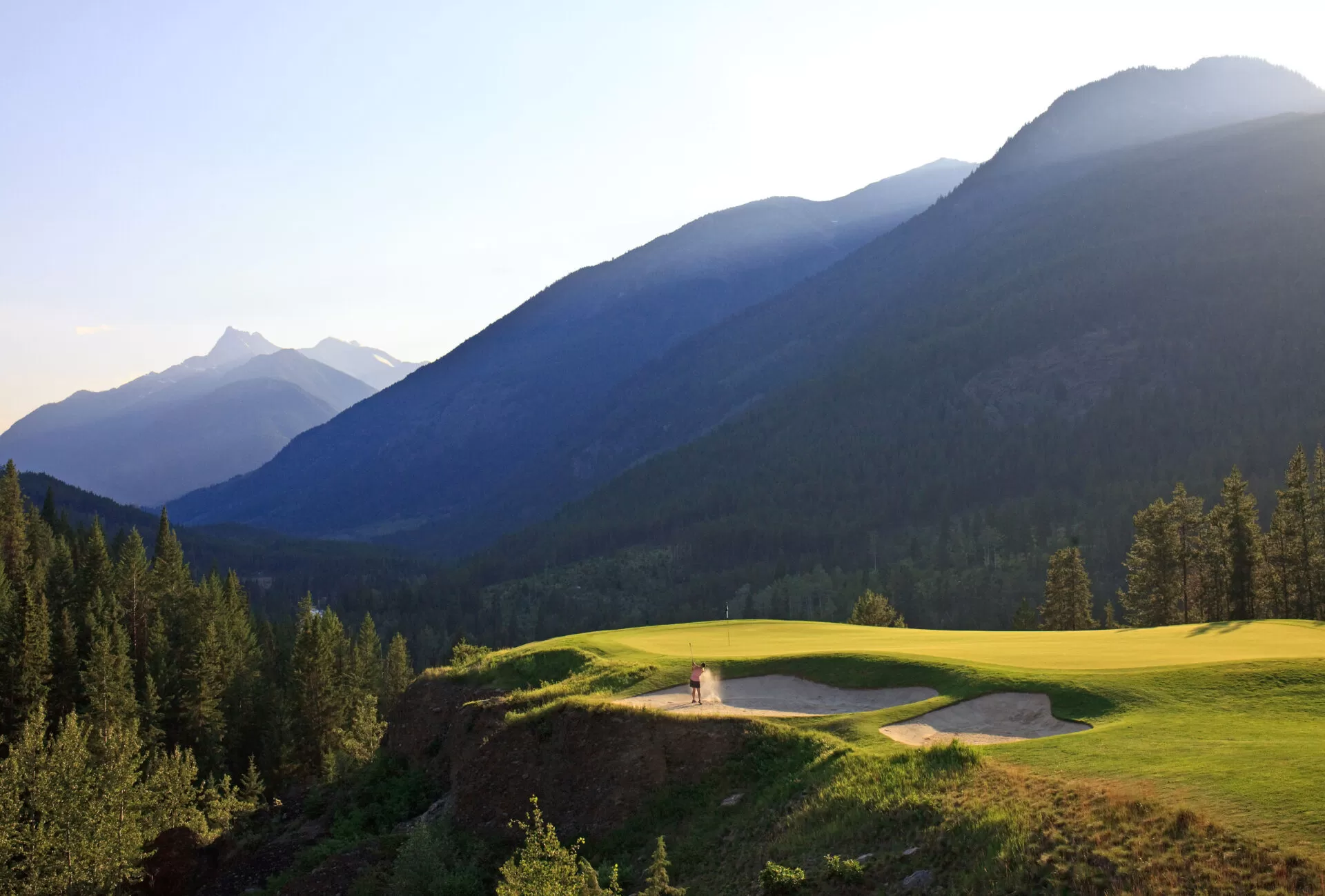Photo of a golfer in the bunker with the mountains in the background